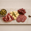 Glencoe Signature Tapasplank met tapas, olijven, kaas, druiven en salami op een rustige lichte achtergrond.
