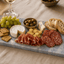 Azul Emerald Signature Tapasplank met kaas, vleeswaren, olijven, druiven en vers brood tijdens een borrel.