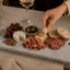 Azul Emerald Signature Tapasplank tijdens een gezellige borrel terwijl iemand een hapje van de plank pakt.