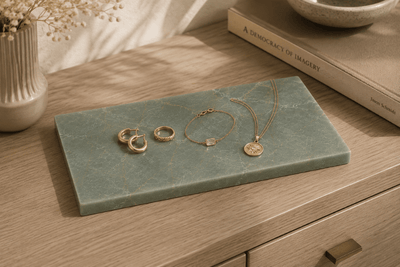Rechthoekige Verde emerald natuurstenen plank met gouden sieraden, horloge, ringen en ketting.