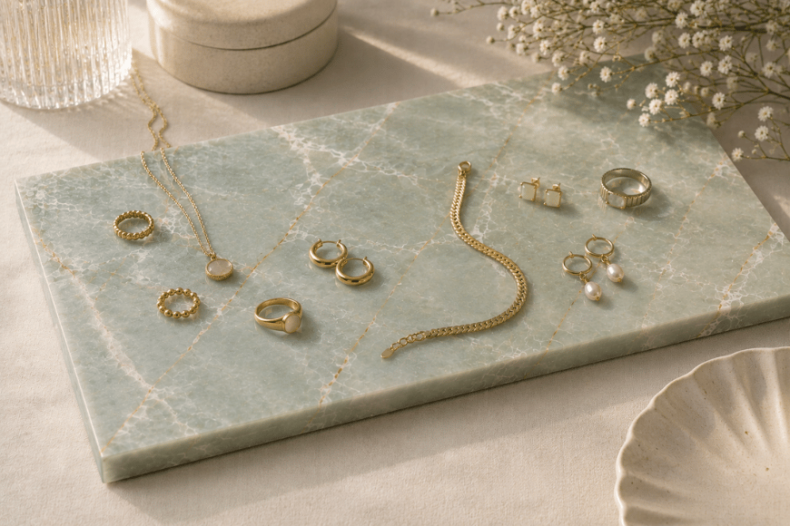 Rechthoekige Verde emerald natuurstenen plank met gouden sieraden, horloge, ringen en ketting.