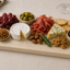 Glencoe tapasplank gevuld met kazen, charcuterie, druiven, olijven en noten voor een stijlvolle borrelpresentatie.