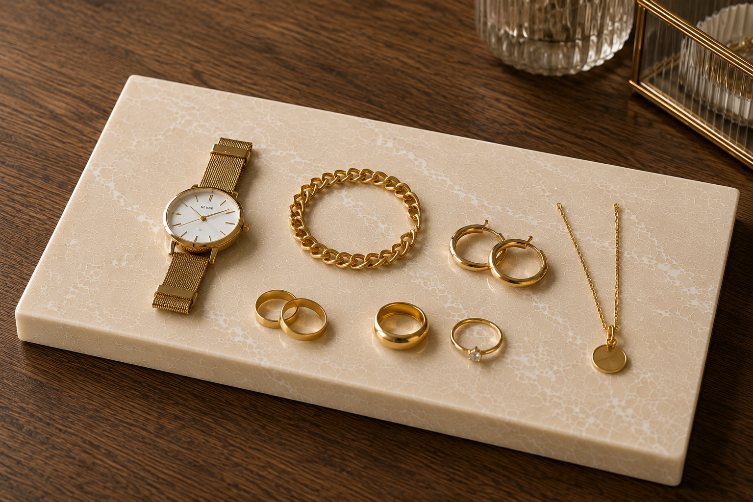 Rechthoekige Glencoe natuurstenen plank met gouden sieraden, horloge, ringen en ketting.