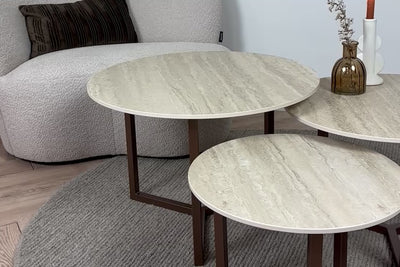 Sfeerbeeld van de 3-delige Salontafel set Travertino Marazzi waarbij de beige keramiek bladen en het Premium onderstel vanuit verschillende hoeken worden getoond.